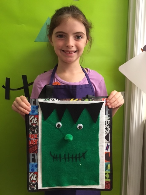 A camper shows off her trick-or-treat bag