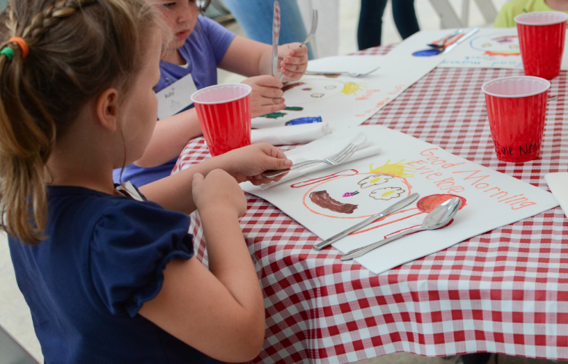  6-7 year olds help each other set the table for lunch 