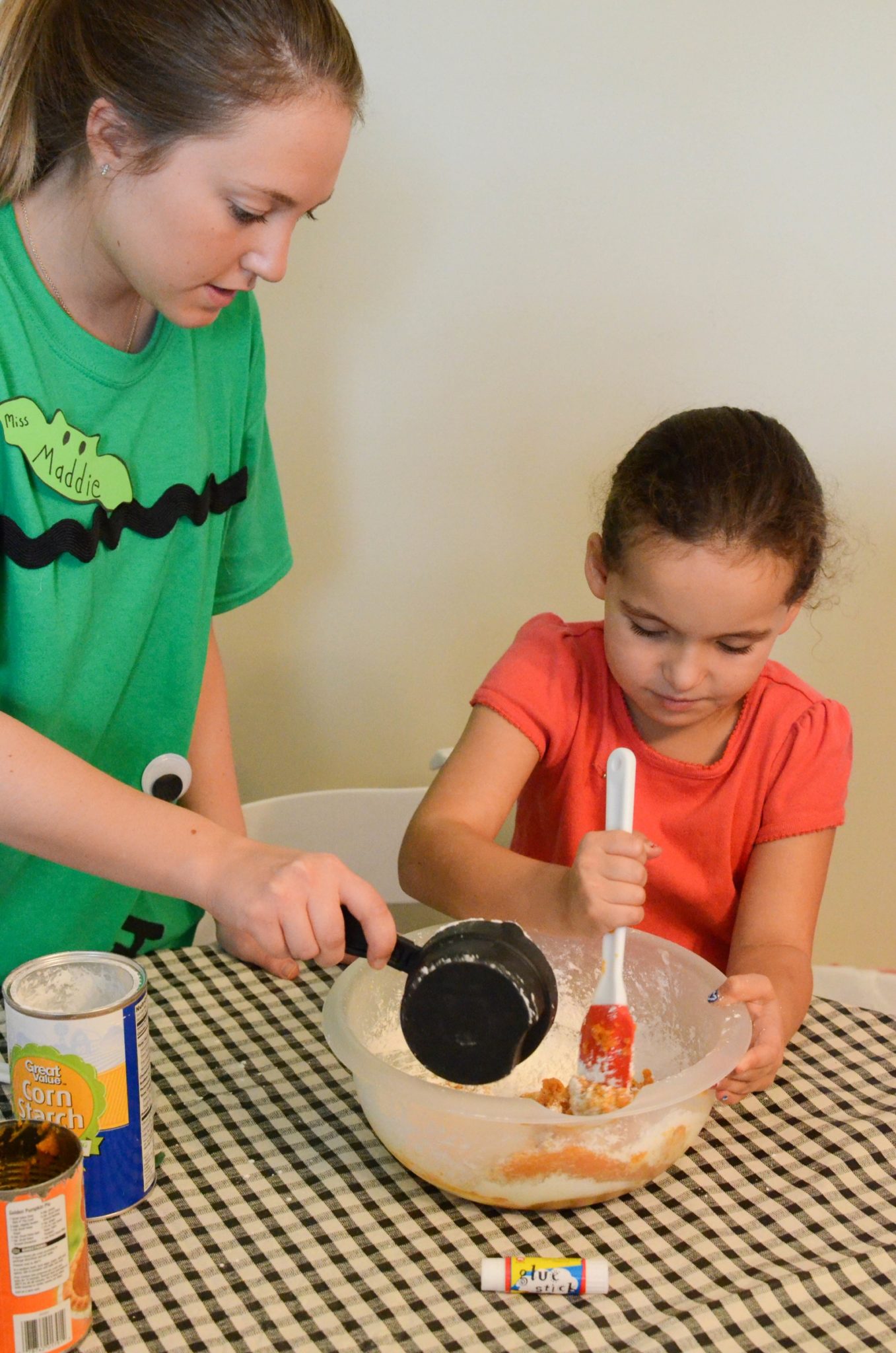 Miss Maddie helps a camper mix up pumpkin play clay
